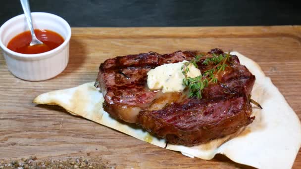 Heerlijke biefstuk. Rundvlees biefstuk op houten bord. Middelgeroosterde biefstuk op een houten plank met saus.  - Video