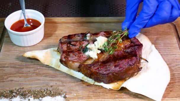Ένας σερβιτόρος με γάντια κόβει μια ζουμερή μπριζόλα. Εστιατόριο σεφ τεμαχισμού μέτρια ψημένο κρέας. - Πλάνα, βίντεο