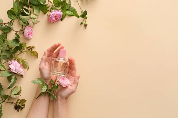 Female hands with perfume and flowers on color background - Photo, Image