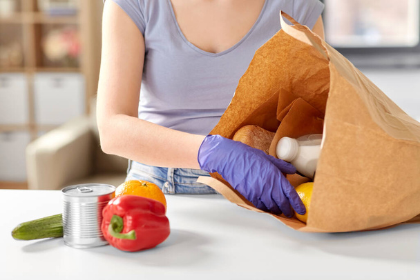 woman in gloves taking food from paper bag at home - Φωτογραφία, εικόνα