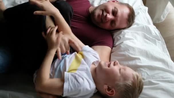 Gelukkig vader en zoon hebben plezier op een bed met, gelukkig familie concept. Uitzicht van bovenaf - Video