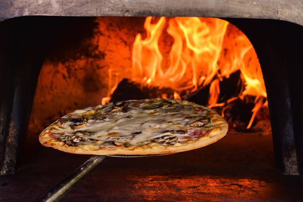 The pizza oven with fire is shot close-up in natural light - Φωτογραφία, εικόνα