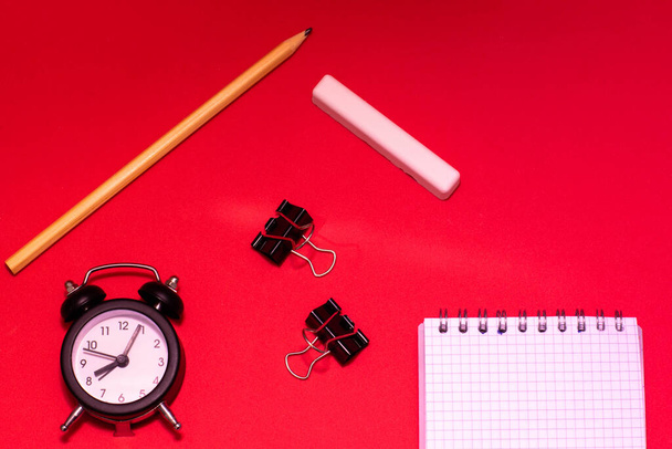 Stationery, alarm clock and notebook on red background. Business Planning Concept. Place for text, copy space. - Zdjęcie, obraz