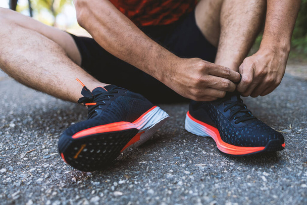 closeup sportman tying running shoes with soft-focus and over light in the background.  fitness, exercise, workout and healthy lifestyle concept. - Foto, imagen