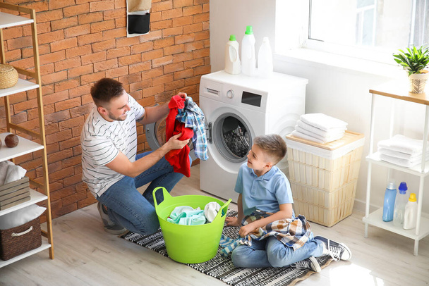 Adam ve küçük oğlu evde çamaşır yıkıyorlar. - Fotoğraf, Görsel