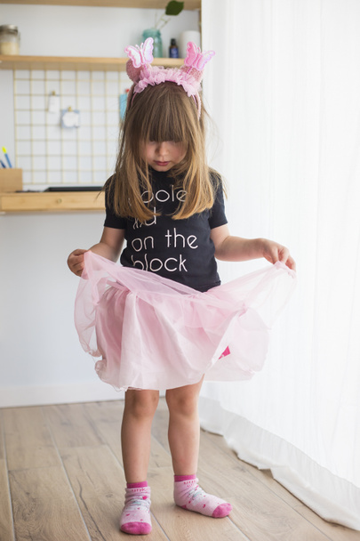 Kleines Mädchen, das zu Hause verkleidet in einem Ballerinakostüm mit rosa Tüll-Tutu, Socken und Antennen spielt - Foto, Bild