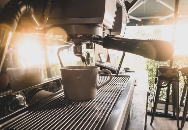 Primer plano del espresso que se vierte de la máquina de café por la elaboración de café profesional. - Foto, imagen