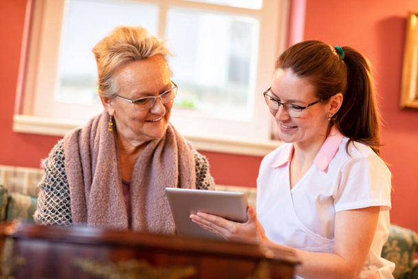 Nurse introducing technology to her patient showing her tablet computer - Foto, Bild