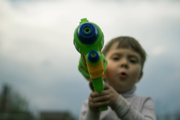 Kleine jongen met een waterpistool op de natuur gericht - Foto, afbeelding