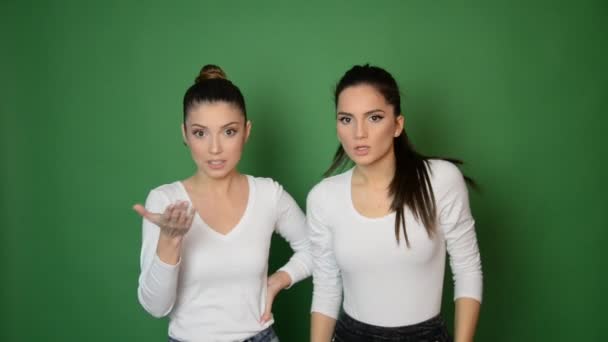 δύο όμορφη νεαρή γυναίκα δείχνει συναισθήματα προς την κάμερα, σε πράσινο φόντο - Πλάνα, βίντεο