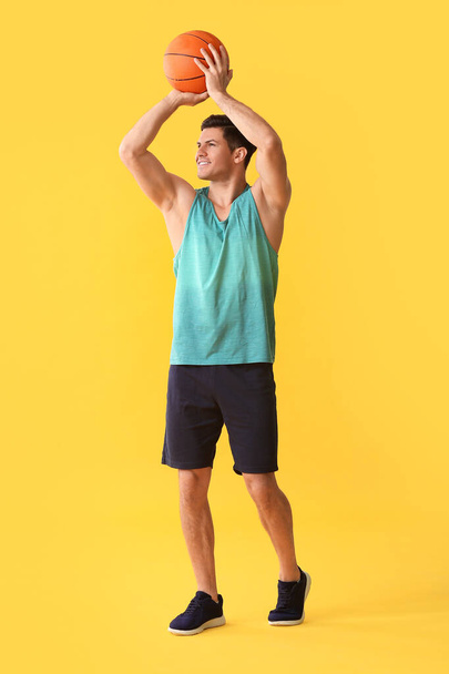 Sporty young man with ball on color background - Φωτογραφία, εικόνα