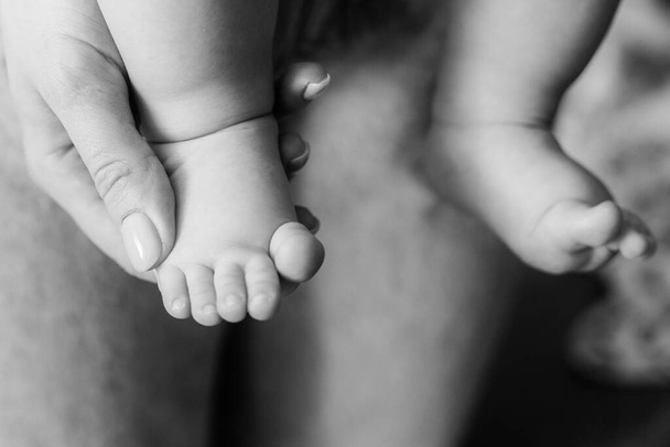 babys first steps. The babys feet take the first steps. photo of childrens legs barefoot. Black and white - 写真・画像