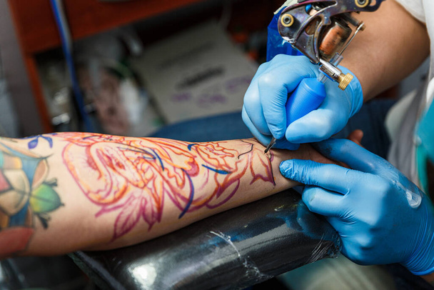 tatuador con su máquina tatuando en el brazo con el diseño dibujado, concepto de arte y diseño
 - Foto, Imagen