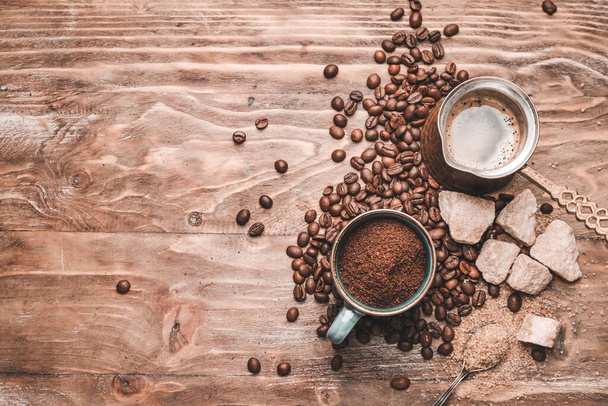Cup with coffee powder, beans, jezve and sugar on wooden background - Photo, Image
