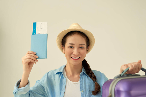 Vrouwelijke reiziger met paspoort en ticket op witte achtergrond - Foto, afbeelding