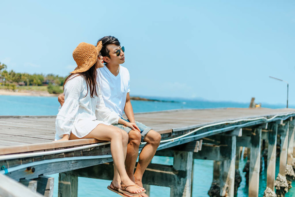 Honeymoon travel couple romantic  hugging and sitting on wood bridge and enjoys their tropical holiday. - Fotó, kép