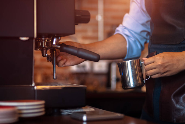 Barista steaming milk in the pitcher with coffee machine for  preparing to make latte art. - Foto, afbeelding