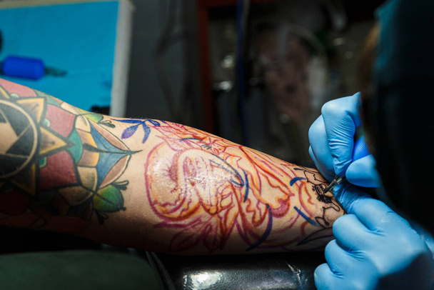 tatuador com sua máquina tatuando no braço com o design desenhado, conceito de arte e design
 - Foto, Imagem