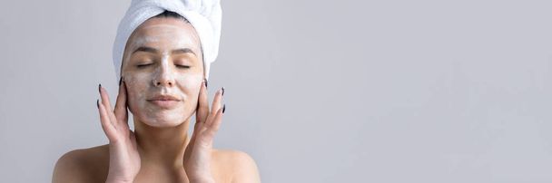 Portrait de beauté de femme en serviette blanche sur la tête applique crème sur le visage. Soin nettoyant éco cosmétique bio spa relax concept. - Photo, image