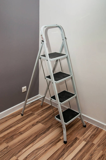 small ladder with four steps standing in the corner of the room - Photo, Image
