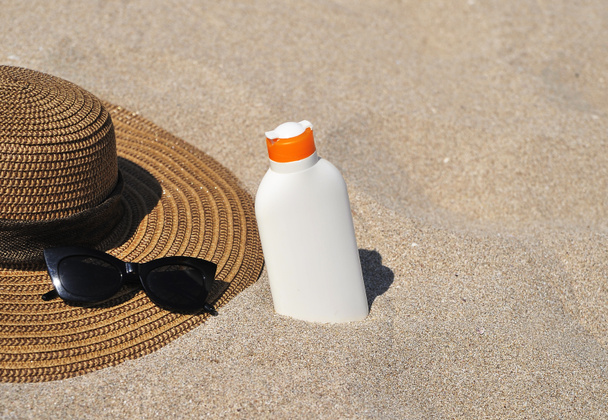 Hattu ja aurinkovoide suojaa hiekalla. Kesäajan käsite. - Valokuva, kuva