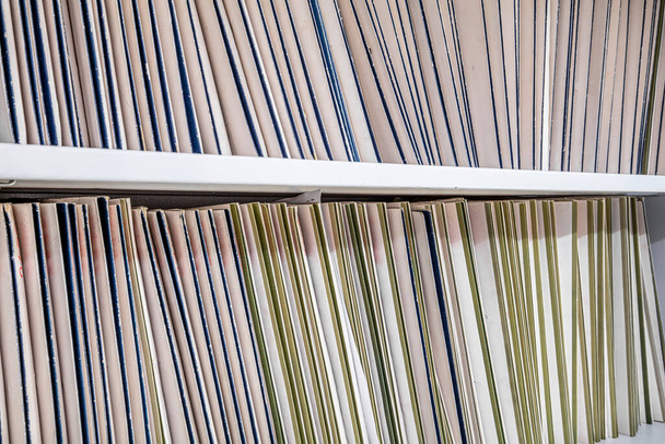 Un estante lleno de carpetas de manila que contienen archivos e información en un espacio de oficina
.  - Foto, Imagen