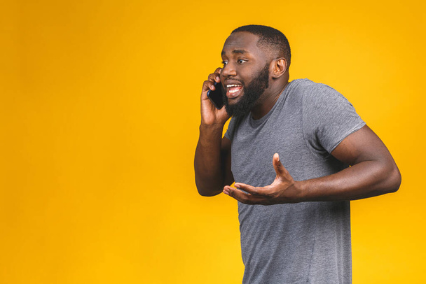 Hombre afroamericano joven usando teléfono inteligente estresado, sorprendido con la vergüenza y la cara sorpresa, enojado y frustrado. Miedo y malestar por error
.  - Foto, Imagen