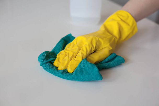 Ręka w jasnożółtych gumowych rękawiczkach czyszczących wyciera powierzchnię stołu - Zdjęcie, obraz