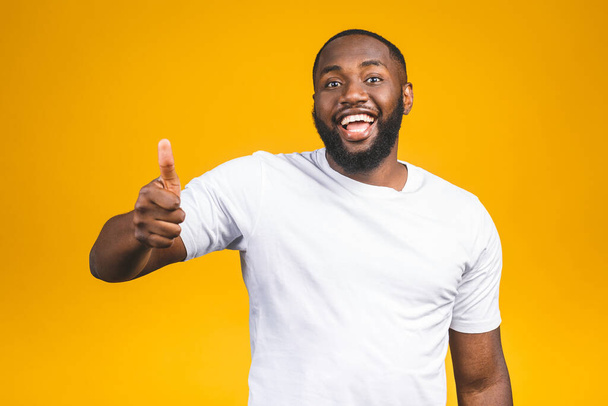Portrét šťastného afroamerického pohledného vousatého muže smějícího se a ukazujícího palec nahoru gesto izolované na žlutém pozadí. - Fotografie, Obrázek