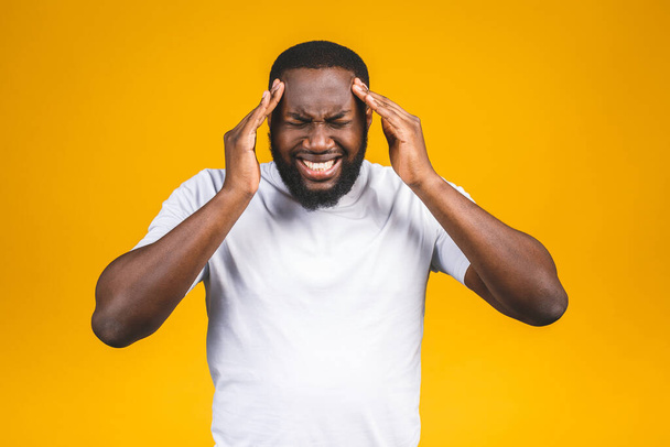 Stressed young african american man feel pain having terrible strong headache concept, tired upset black guy massaging temples suffering from migraine isolated on yellow studio blank background - Foto, immagini