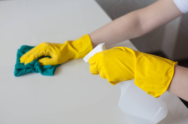 El hombre limpia una mesa con guantes de limpieza de goma y rocía un limpiador antiséptico
 - Foto, imagen