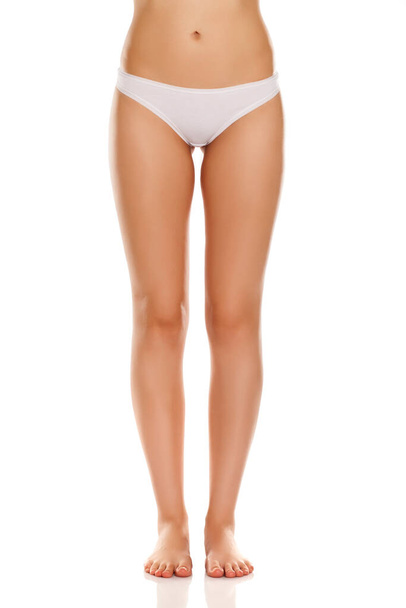 Weibliche nackte Beine mit weißen Höschen auf weißem Hintergrund - Foto, Bild