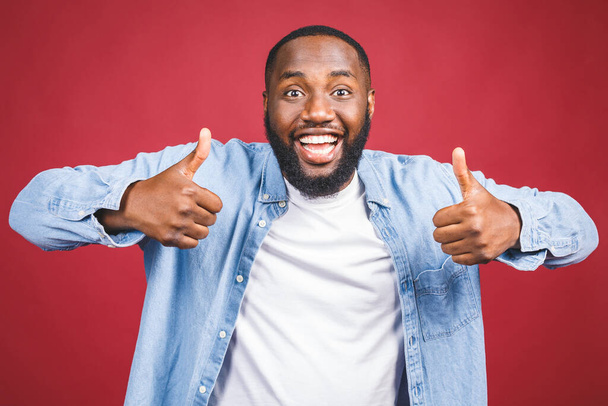 Porträt eines glücklichen afrikanisch-amerikanischen Mannes isoliert über rotem Hintergrund. Daumen hoch.  - Foto, Bild