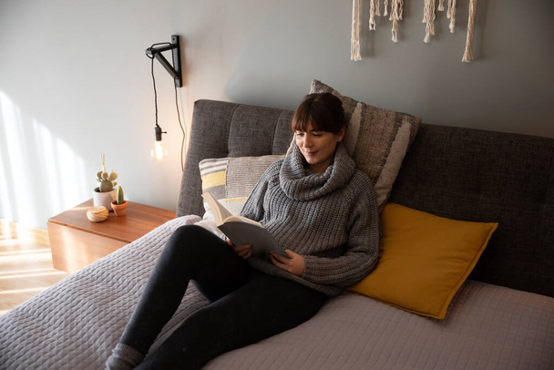 Όμορφη γυναίκα στο κρεβάτι και διαβάζοντας ένα βιβλίο - Φωτογραφία, εικόνα