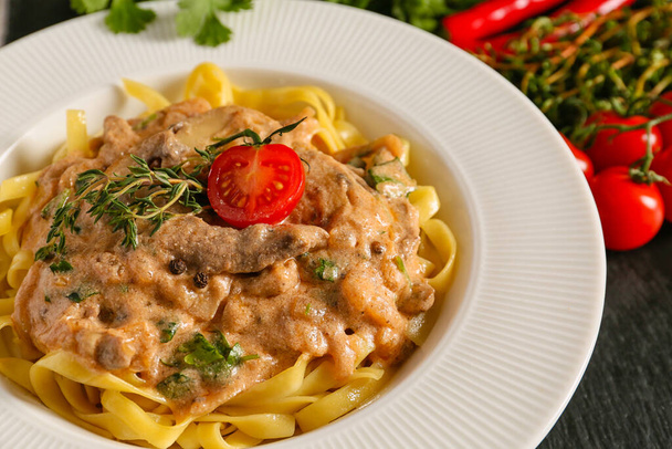Bord met smakelijk rundvlees stroganoff en pasta, close-up - Foto, afbeelding
