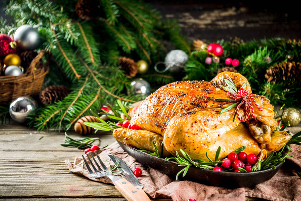 Traditional Christmas and Thanksgiving roasted whole chicken with fruit and rosemary. Rustic wooden christmas table, with xmas tree branches and decorations copy space - Foto, Imagen