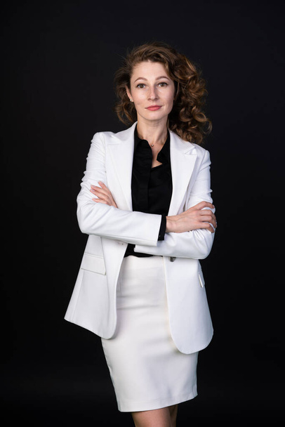 Femme d'affaires élégante en costume blanc debout avec les bras croisés, elle est calme et confiante
 - Photo, image