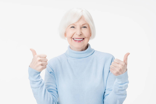 Senior woman showing thumbs up gesture smiling on white background - Foto, Imagem