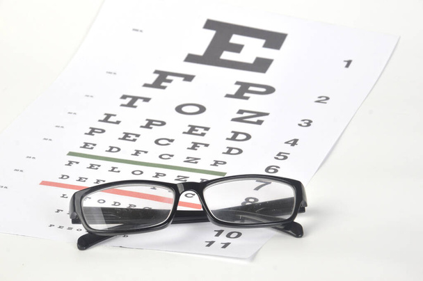 Gafas oculares en el fondo de la tabla de prueba de la vista de cerca - Foto, Imagen