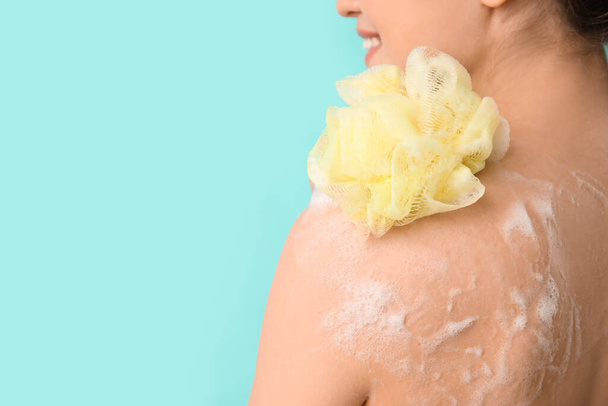 mooie jonge vrouw nemen douche op kleur achtergrond - Foto, afbeelding