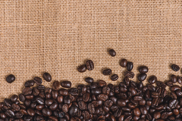 Κοντινό πλάνο καβουρντισμένο κόκκους καφέ σε σάκο φόντο με αντίγραφο χώρο - Φωτογραφία, εικόνα