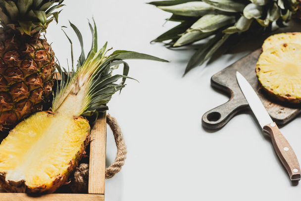 selective focus of fresh cut pineapple on wooden tray and cutting board with knife on white background - Photo, image