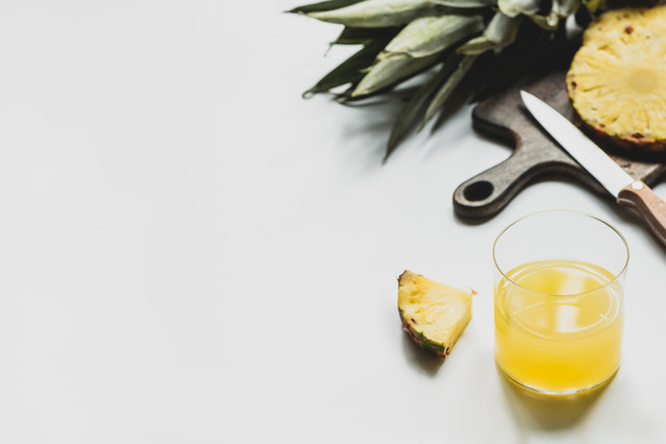 白を基調としたナイフでまな板においしい果物を切る近くの新鮮なパイナップルジュースの選択的な焦点 - 写真・画像