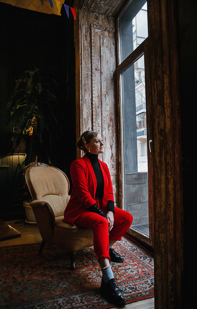 lovely blonde girl in a red jacket and shoes and a blue jacket posing in a vintage interior - Foto, immagini