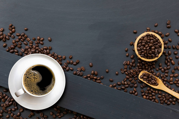 kopje koffie en bonen op zwarte houten tafelondergrond. bovenaanzicht - Foto, afbeelding