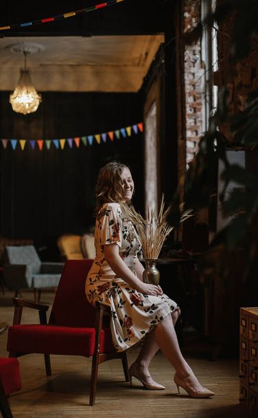 lovely blonde girl in floral dress posing  in a vintage interior - Фото, изображение