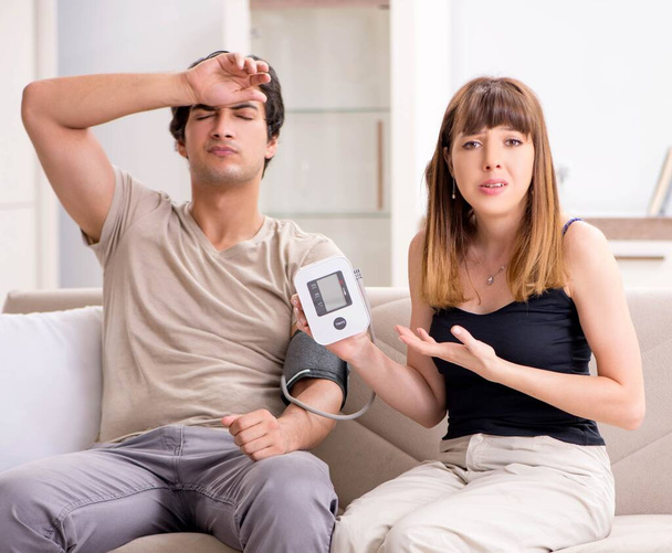 夫の血圧をチェックする妻 - 写真・画像