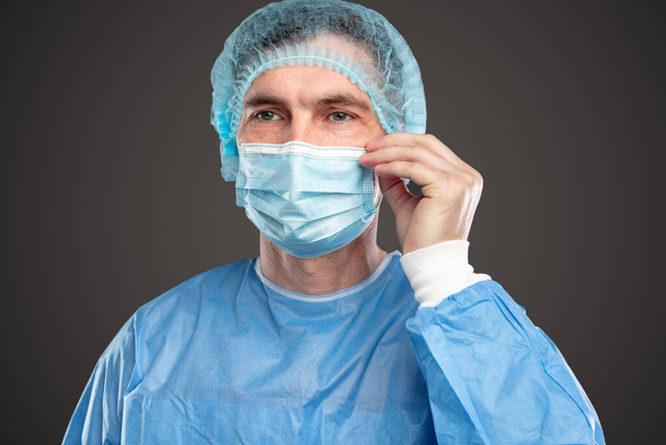 Serious doctor adjusting medical mask - Фото, изображение