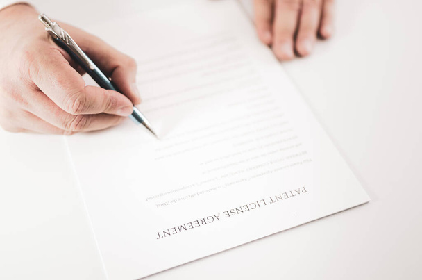 Encerramento de um empresário que assina um contrato de Contrato de Licença de Patentes com uma caneta. - Foto, Imagem