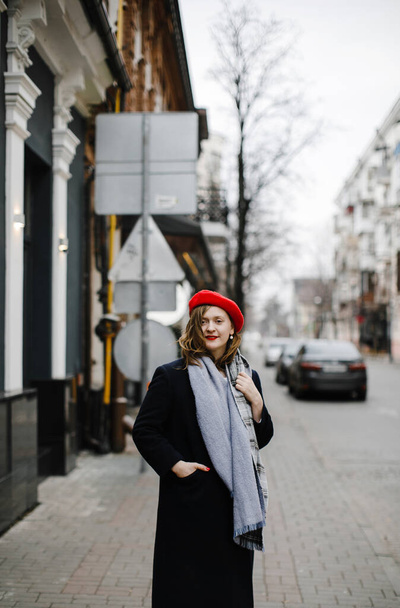 colorful blonde girl in a red hat, coat and scarf on a walk in the city smiling - Fotoğraf, Görsel